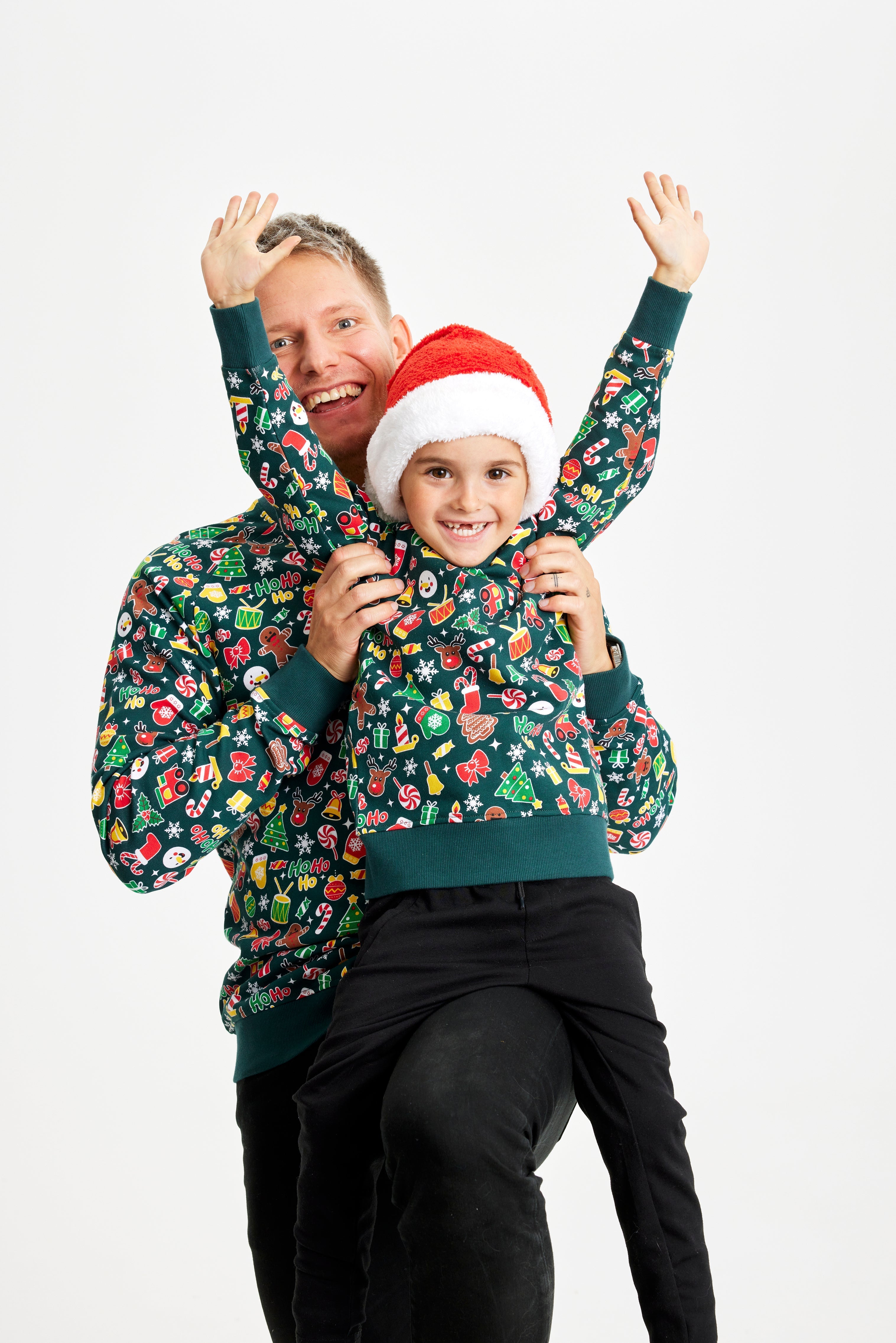 En mand og et barn poserer sammen iført grønne julesweatre med mønster.